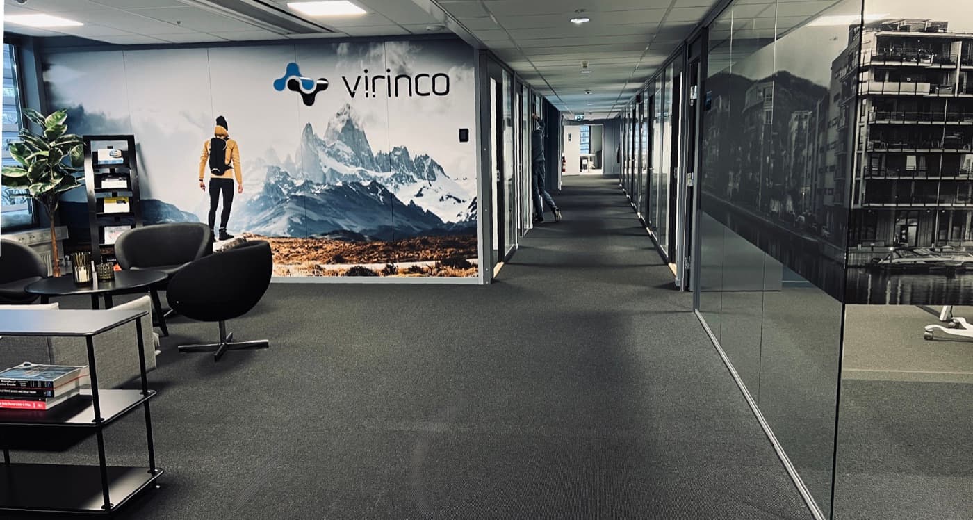 A bright lounge and seating area in the Grønland 1 office, with a Virinco-branded wall mural.