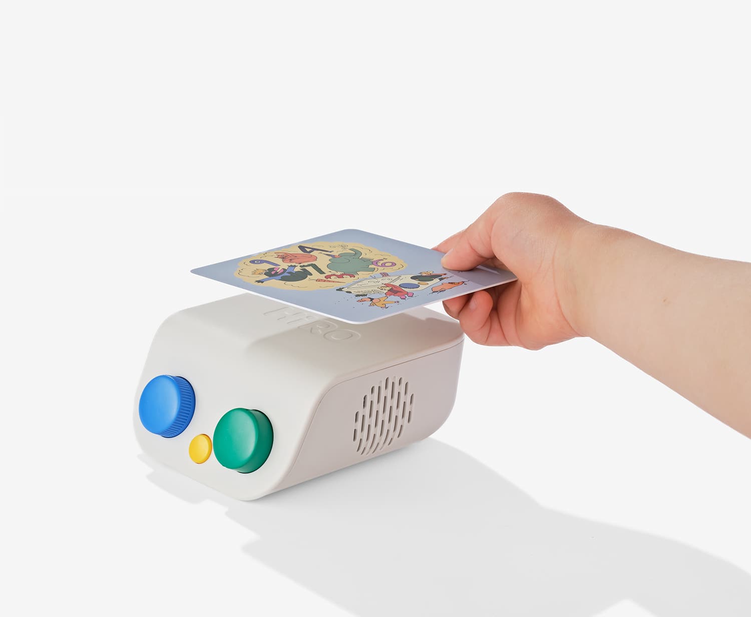 A hand tapping an illustrated story card on top of the white HiRO speaker.